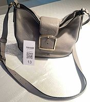 Full view of grey Kate Spade crossbody bag showing strap and shape
