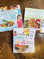 Front covers of the three cookbooks displayed on wooden surface