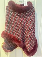 Full view of plaid cape on hanger showing fur collar and hem