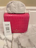 Front view of croc-embossed pink Kate Spade Staci square crossbody with tag and protective packaging