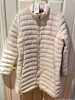 Front view of ivory Patagonia puffer jacket hung on door