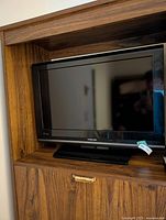 Front view of 26-inch Toshiba TV on stand within wooden cabinet