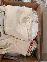 Box with folded white linens and knit holiday fabric