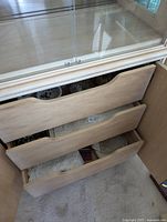 Three hutch drawers partially opened showing linens in lower drawer