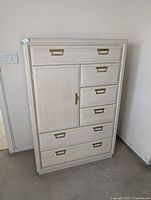 Front view of tall cream dresser with brass hardware