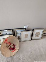 Framed prints and hat grouped against wall