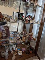 Overall view of three bottom shelves with assorted figurines, mugs, book and decor