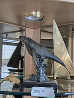 Front view of bronze humpback whale sculpture with sailboat and dolphin partially visible