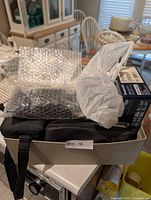 Tray containing bubble-wrapped camera, cases, cords, Lumix box