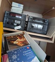 Hitachi stereo units stacked with CD cases above and box of CDs in foreground