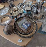 Group shot of all silver plated items including tea service, plates, goblets, caviar dome and polish