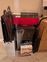 Overview of stacked boxed items, briefcase, Magic Bag, CDs, plate stands