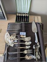 Flatware set, serving pieces and souvenir spoons laid out in felt roll