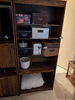 Bookshelf section showing several storage boxes, planter and folded duvet