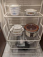 Full view of shelf showing all cookware, slow cooker, fruit basket