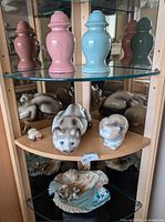 Full view of items on glass shelves: candle holders, cat figurines, raku bowl