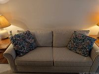 Front view of striped sofa with two floral pillows