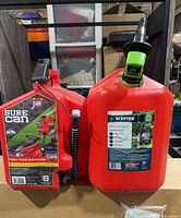 Front view of both 5-gallon gas cans showing brand labels and spouts