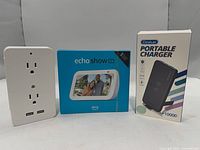 Front view of all three boxed items: Echo Show 5, Dodoplay Portable Charger, wall outlet adapter