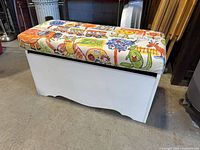 Closed toy chest showing padded seat and white body