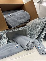 Box with multiple rolled grey Scott Living towels and one towel inside pop-up bin