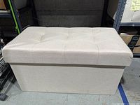 Front view of beige upholstered storage ottoman