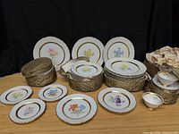 Stacked dinner, salad and dessert plates with floral motifs, gold rims, plus teacups and saucers