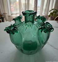 Angled view showing teal glass vase, front and side spouts, ruffled rims