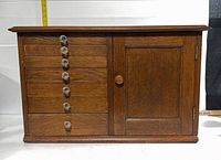Front view showing seven drawers with glass knobs and right cabinet door