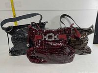 Group view of three croc-embossed Brighton handbags