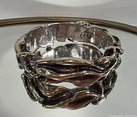 Full view of sterling silver branch-style bangle resting on mirror
