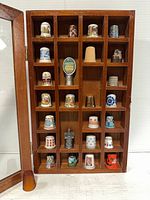 Front view of wooden display case showing all thimbles