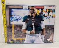 Full view of signed photo in sleeve with ruler for scale