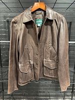 Full front view of brown leather jacket on hanger
