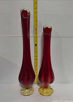 Full view of both amberina swung vases with measuring tape