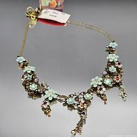 Full view of necklace showing floral motif and tag