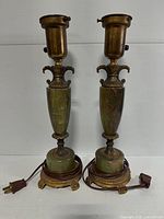 Full view of both brass and green marble table lamps, cords coiled at bases