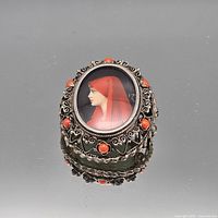Front view showing portrait under glass with red cabochon decorated silver-tone frame
