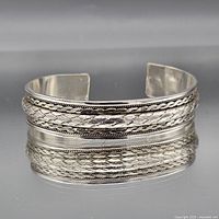 Front view of sterling silver open cuff bracelet showing braided rope inlay and twisted rope borders