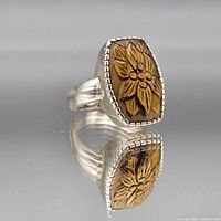 Front view showing carved wood floral centerpiece and beaded bezel