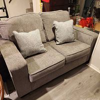 Full view of gray two-seat sofa with pillows