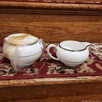 Creamer and wrapped covered sugar bowl on step