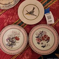 Front view of three plates showing floral designs and bird artwork