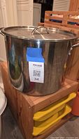 Large stainless steel stock pot with lid on wooden stand