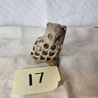 Front view of carved sandstone owl showing cutout lattice body and facial detail