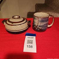 Stoneware lidded soup bowl and mug on red surface