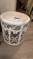 Cylindrical white wicker plant stand, side view showing scroll lattice