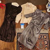 All three garments laid out: brown dress, beige blouse, silver dress with bolero