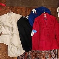 Four women’s suits laid out: ivory, black, royal blue, red