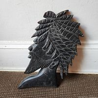 Full view of carved wooden bust standing against wall